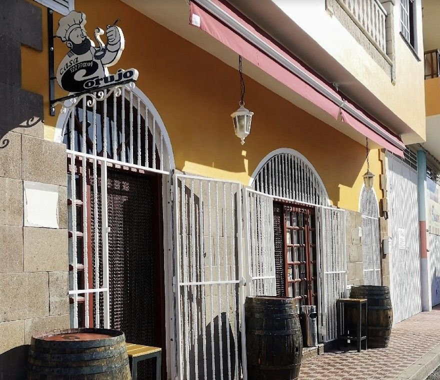 Fachada de Casa Corujo en Granadilla de Abona, con toneles de madera y rejas blancas de forja